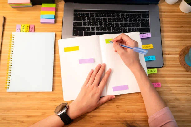Femme écrivant dans un carnet avec des post-it colorés pour organiser un evjf à Montpellier