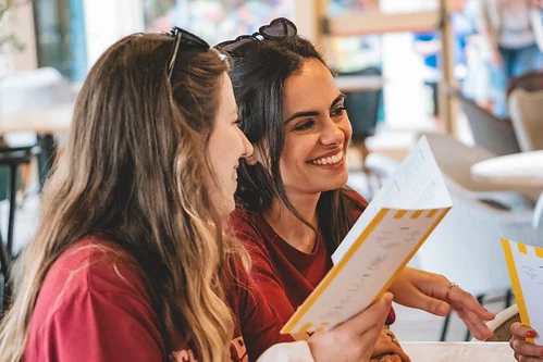 deux femmes evjf souriantes lisent un menu lors d un cours de cuisine a deauville pour evjf
