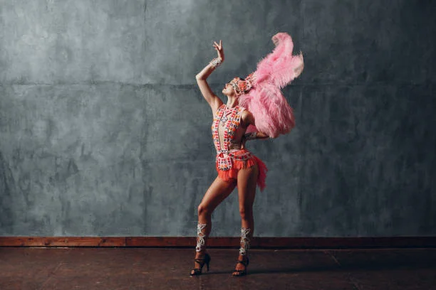 Cours de danse cabaret ou effeuillage EVJF à Strasbourg, danseuse en costume à plumes roses posant avec élégance sur scène