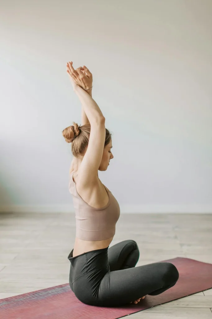 Participant assis en posture de yoga bras levés lors d’un cours EVJF à Rennes.
