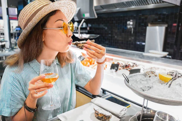femme degustant des huitres avec un verre de vin lors d un evjf a montpellier dans un bar a huitres