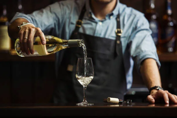 alt="Dégustation vins d’Alsace EVJF à Strasbourg, serveur versant un verre de vin blanc dans une ambiance conviviale et élégante"