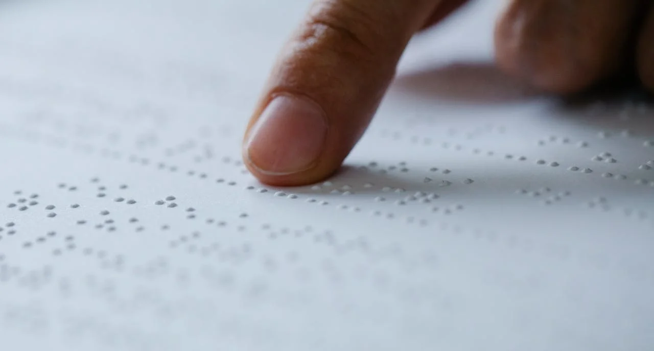 Image d’un doigt parcourant du braille, parfaite pour illustrer l’accessibilité, le toucher et la communication sensorielle.