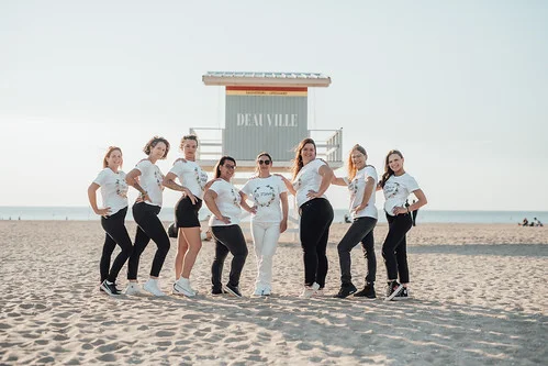 groupe de femmes posant sur la plage de deauville lors d un evjf en t shirt blanc et noir devant une cabane de sauveteur
