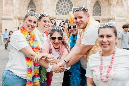 quelles sont les activites pour un evjf a reims participants a un evjf et evg a reims riant ensemble devant la cathedrale avec lunettes et accessoires colores