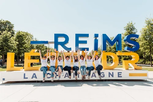 comment organiser un enterrement de vie de jeune fille a reims groupe de femmes en t shirt evjf posant devant le grand lettrage reims champagne lors d un enterrement de vie de jeune fille