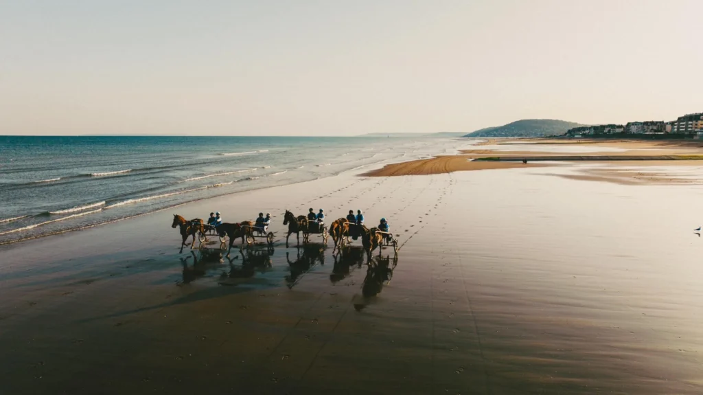 Vue aérienne de sulkys et chevaux galopant sur la plage de Cabourg