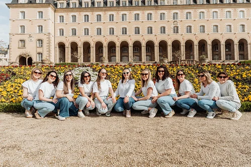 groupe de femmes en jean et chemise blanche pose devant un massif de fleurs