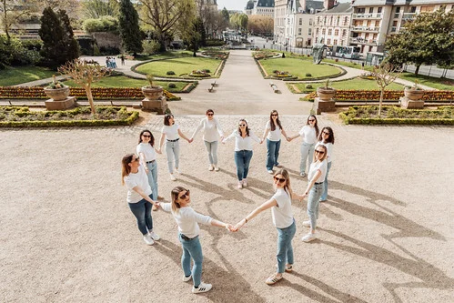 groupe de femmes en jean et chemise blanche formant un cercle pour un evjf tout compris a rennes dans un parc