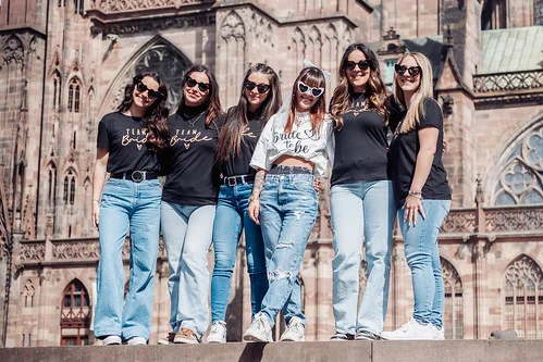 groupe de femmes celebrant un evjf tout compris a strasbourg pose devant la cathedrale avec la mariee au centre