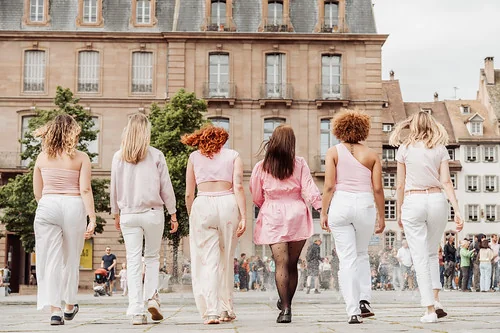 groupe de femmes en tenues roses marchant ensemble sur une place animee