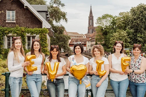 groupe de femmes celebrant un evjf tout compris a strasbourg avec ballons lettres et cathedrale visible en arriere plan