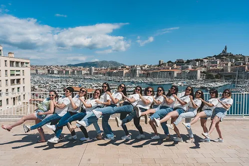 grand groupe de femmes alignees en pose choregraphiee avec vue sur le vieux port de marseille pendant un evjf