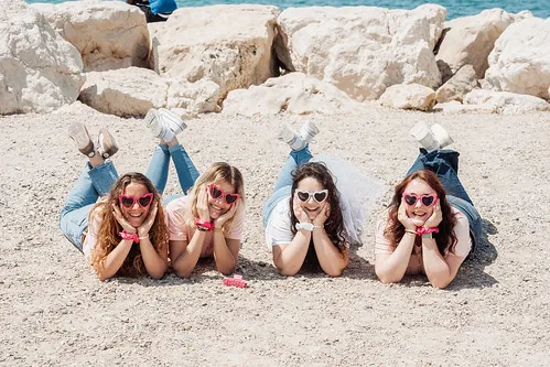 quatre femmes allongees sur le sable avec des lunettes coeur roses lors d un evjf a marseille