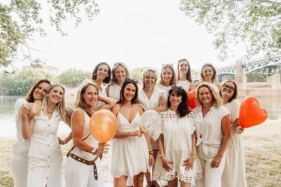 groupe de femmes en robes blanches celebrant un evjf tout compris a toulouse au bord de la garonne avec ballons