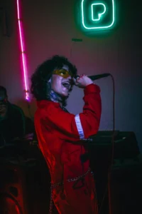 Femme en tenue rouge chantant au karaoké EVJF à La Baule avec micro et lumières néon.