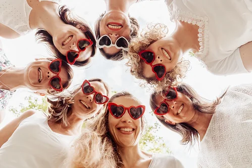 Amies souriantes en cercle avec des lunettes en forme de cœur 