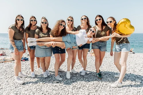 Groupe de jeunes femmes à Nice tenant la future mariée en l’air lors d’un EVJF inspiré de Koh Lanta sur la plage