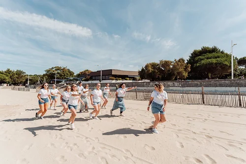 groupe de femmes en t shirts blancs et shorts court sur le sable courant ensemble lors dun evjf esprit koh lanta a la rochelle