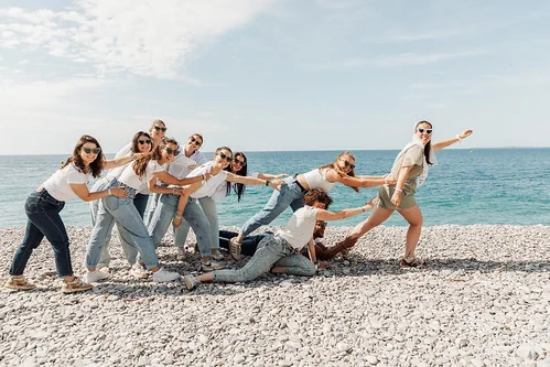 Jeunes femmes jouant à tirer la future mariée sur la plage à Nice lors d’un EVJF fun et original inspiré de Koh Lanta