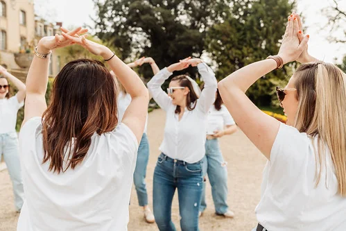 femmes en jeans et chemise blanche faisant un jeu en plein air style koh lanta evjf a rennes