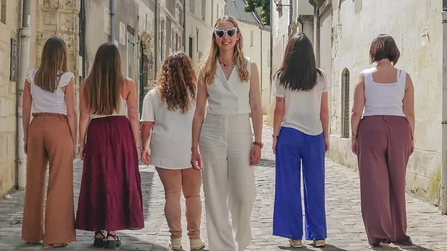 future mariee en blanc entouree de ses amies marchant dans une rue pavée lors du deroulement d un shooting photo evjf a tours