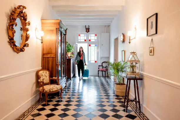 femme avec valise entrant dans une maison d hotes elegante avec deco ancienne 