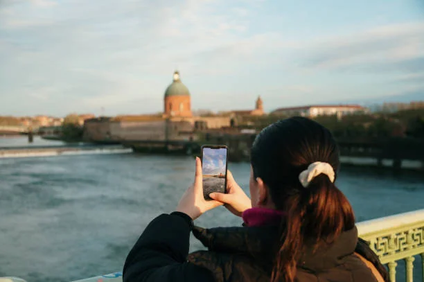 femme prenant une photo de la garonne et du dome de la grave a toulouse lors d un sejour evjf avec logement proche du centre