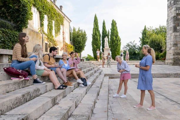 groupe de jeunes assis sur des marches discutant ensemble devant un monument historique