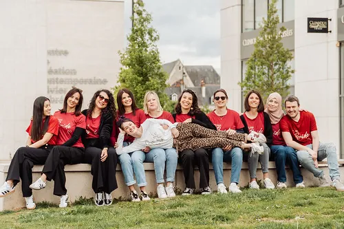 groupe de femmes en t-shirts rouges pose en ville à Tours avec une amie allongée sur leurs genoux, illustrant où dormir pour un evjf à tours