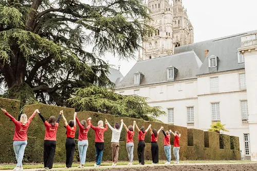 groupe de femmes en t-shirts rouges, mains levées devant un bâtiment à Tours, illustrant pourquoi aller à tours pour un evjf