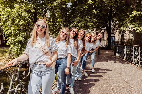 pourquoi choisir un shooting photo evjf à bordeaux : groupe d amies en file indienne souriantes sur un pont verdoyant