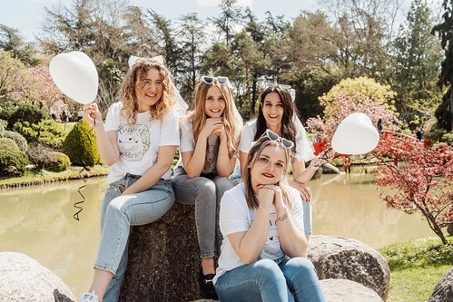 quatre amies en jean et t shirt blancs avec ballons celebrant un evjf a toulouse dans un parc au printemps