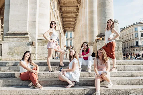 quand organiser un evjf à bordeaux : groupe d amies posant sur les marches d un monument avec colonnes en plein centre ville