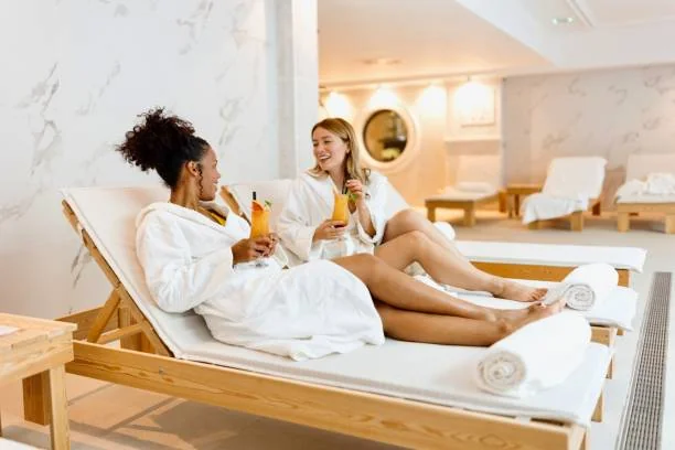 Deux amies en peignoirs blancs se détendent sur des transats avec des cocktails colorés lors d’un spa EVJF à Nantes.