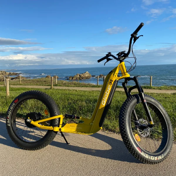 Trottinette electrique jaune stationnee sur un chemin côtiers face a l ocean Atlantique.