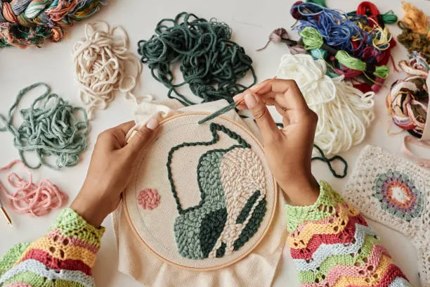mains d une femme realisant une creation textile lors d un atelier broderie