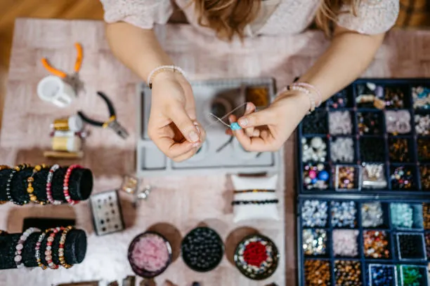 mains d une femme fabriquant un bracelet lors d un atelier creation de bijoux
