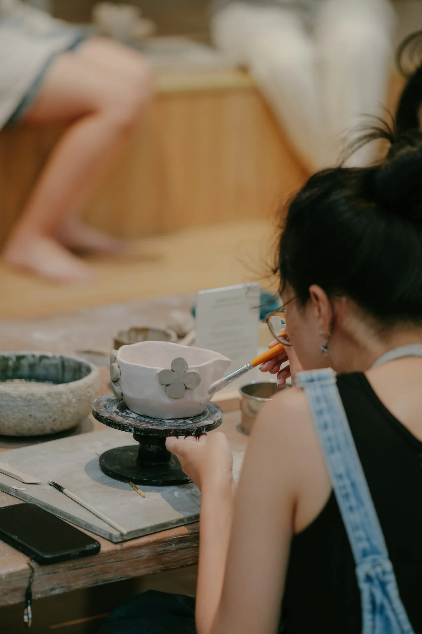 Jeune femme peignant un bol en céramique pendant un atelier créatif à domicile.