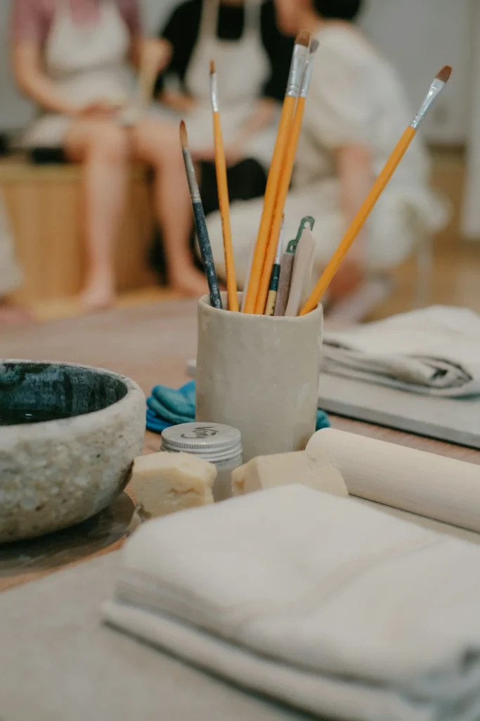 Ensemble de pinceaux et outils utilisés pendant un atelier de peinture sur céramique.