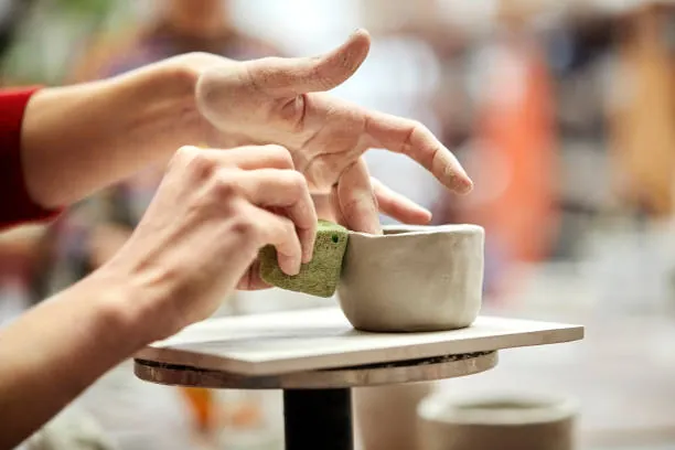 mains d une femme modelant une piece en argile lors d un atelier poterie