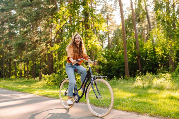jeune femme souriante fait une balade a velo dans un parc