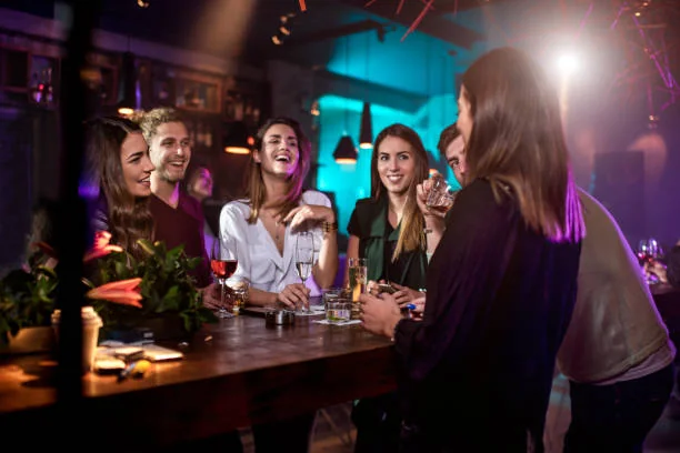 Groupe d’amies riant autour d’un comptoir moderne dans un bar branché à Nantes pendant un EVJF
