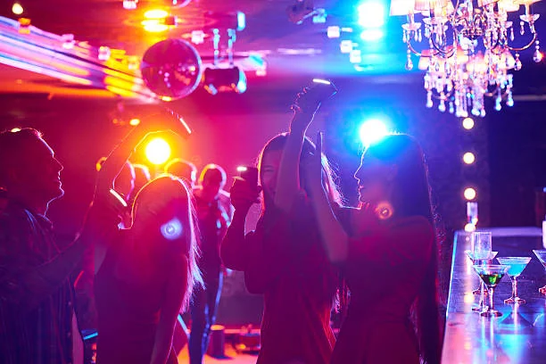 Groupe d’amies dansant sous des lumières colorées dans un bar festif à Nantes pendant un EVJF
