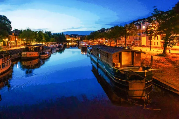 Vue nocturne du canal de Nantes avec péniches éclairées et reflets sur l’eau