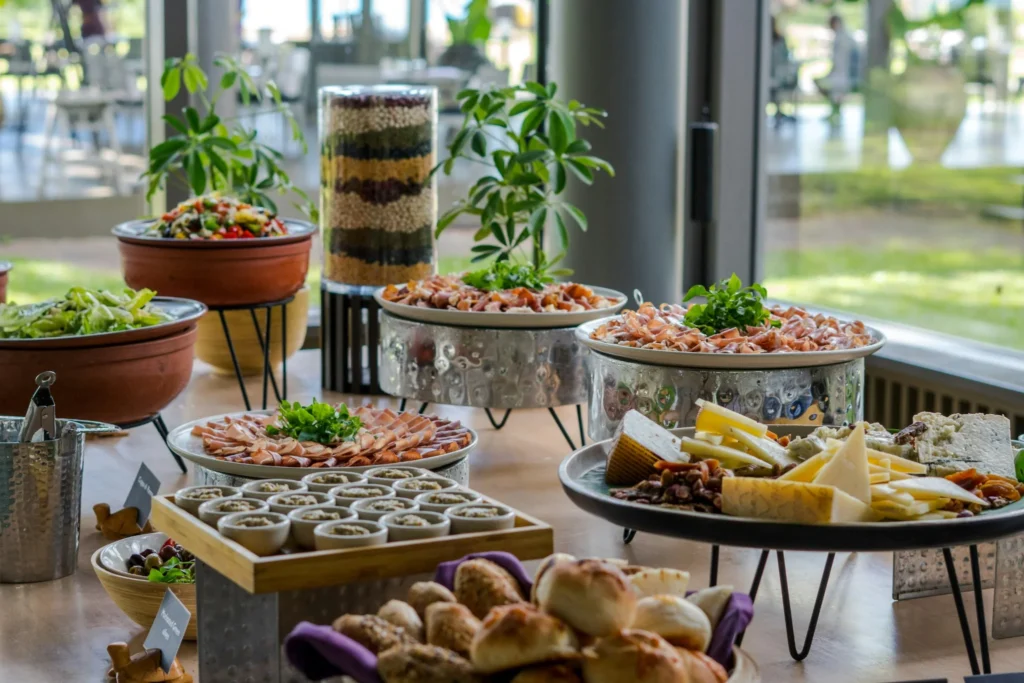 Buffet de brunch varié avec salades, fromages et charcuterie dans un cadre lumineux près de la mer