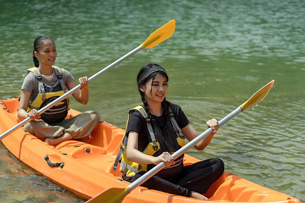 Deux amies pagaient dans un canoë orange, profitant d’une balade conviviale sur l’eau.