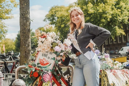 future mariee souriante posant avec un velo fleuri lors d’un city game evjf à amsterdam