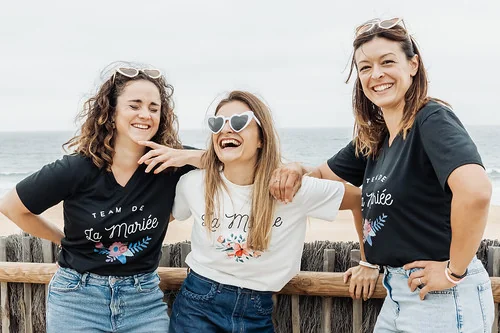 Trois filles en EVJF rient ensemble face a l ocean ambiance detendue