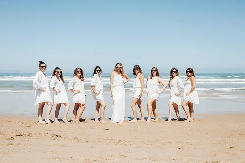 Groupe de filles en robes blanches pose sur la plage de Biarritz pendant un city game evjf biarritz face a l ocean